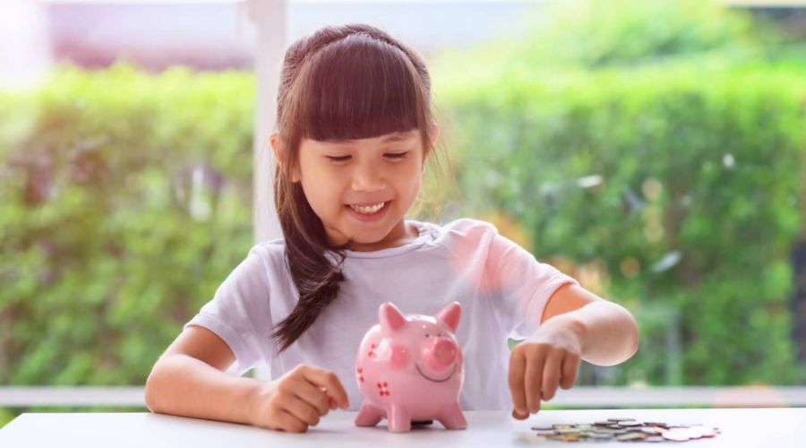 happy young girl saving money in her piggy bank